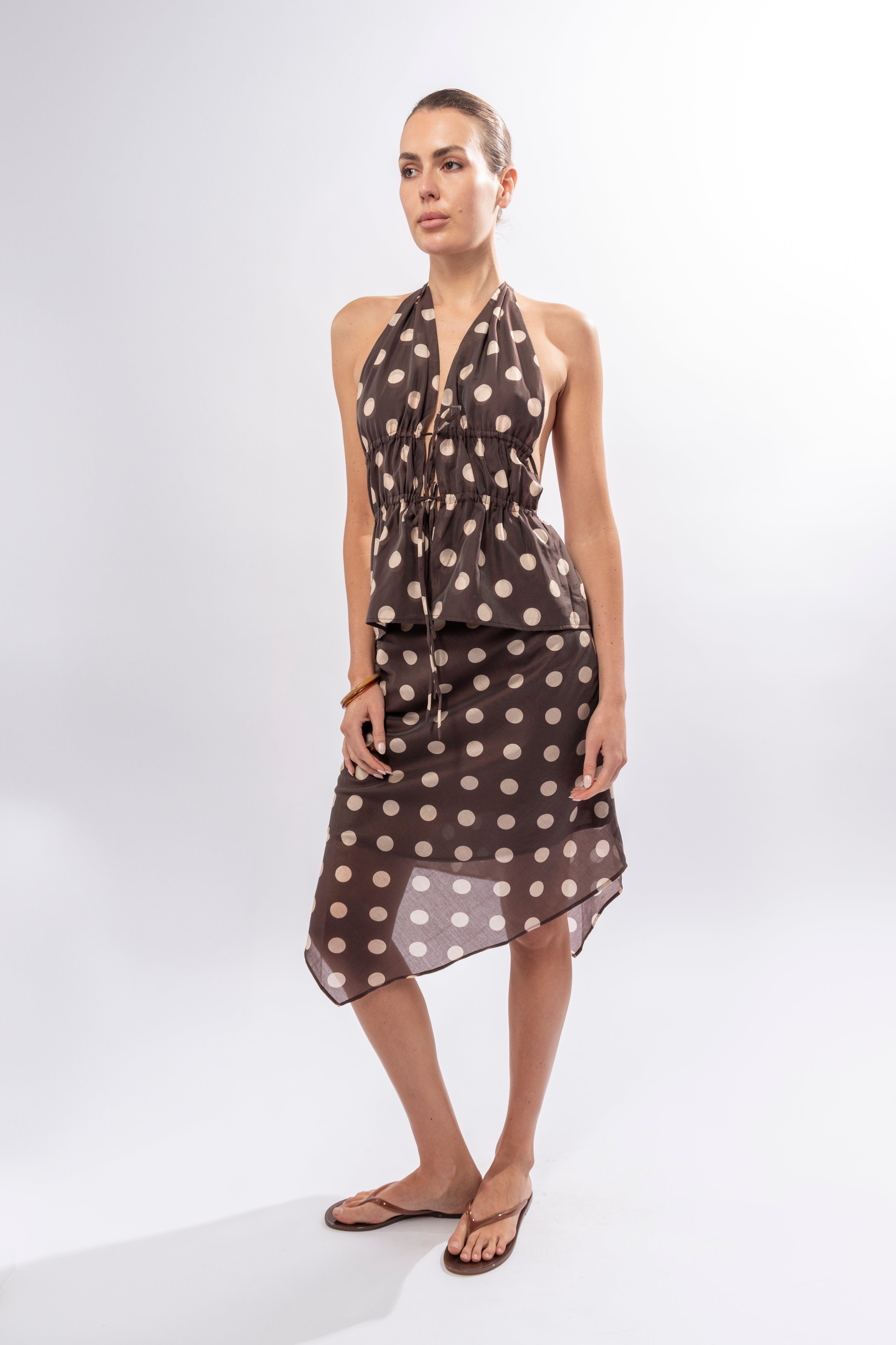 Model wearing brown polka dot halter top styled with matching skirt